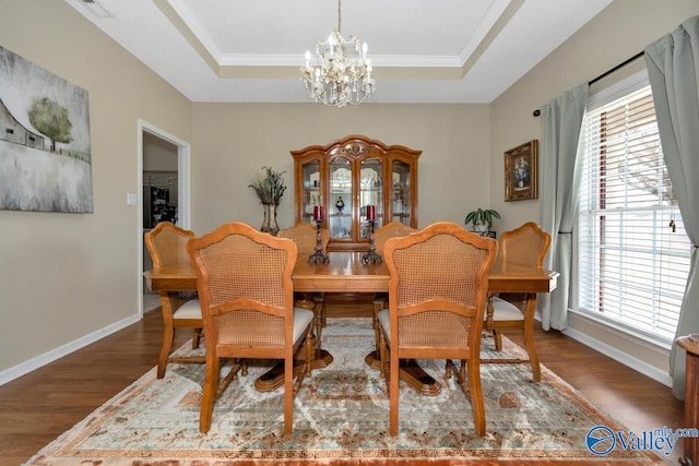 dining room featuring a tray ceiling, an inviting chandelier, baseboards, and wood finished floors