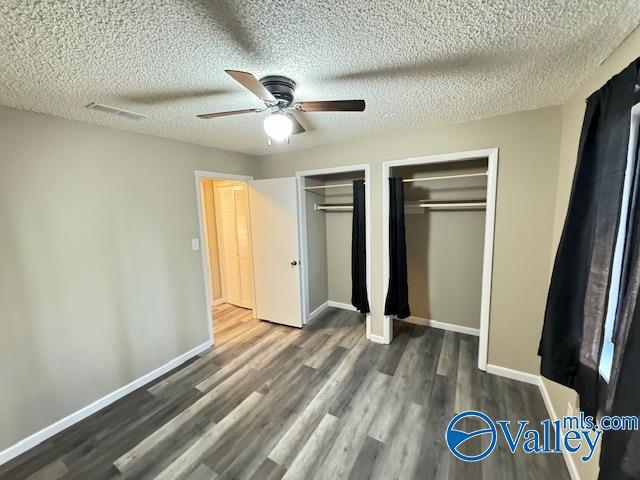 2950 Hood Rd SW Unit J, Huntsville, AL 35805 - unfurnished bedroom with a textured ceiling, two closets, baseboards, wood finished floors, and visible vents