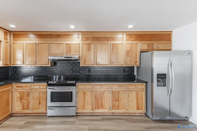 kitchen featuring dark stone counters, appliances with stainless steel finishes, light wood-type flooring, and under cabinet range hood