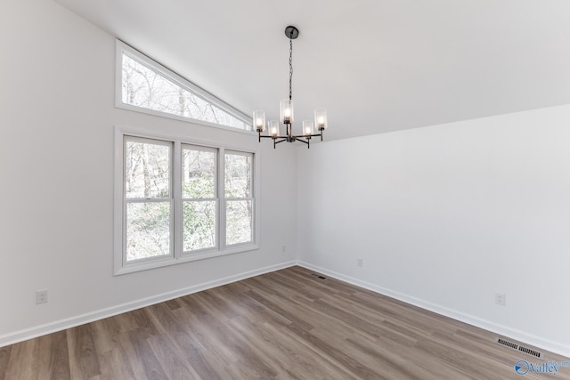 unfurnished room featuring baseboards, visible vents, wood finished floors, vaulted ceiling, and a chandelier