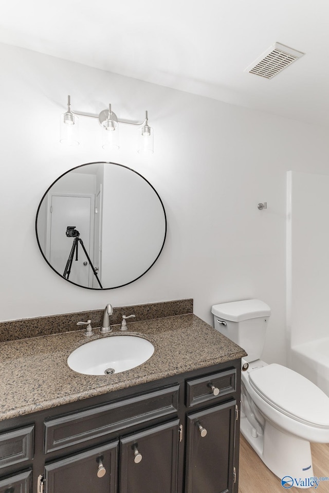 bathroom with toilet, visible vents, wood finished floors, and vanity