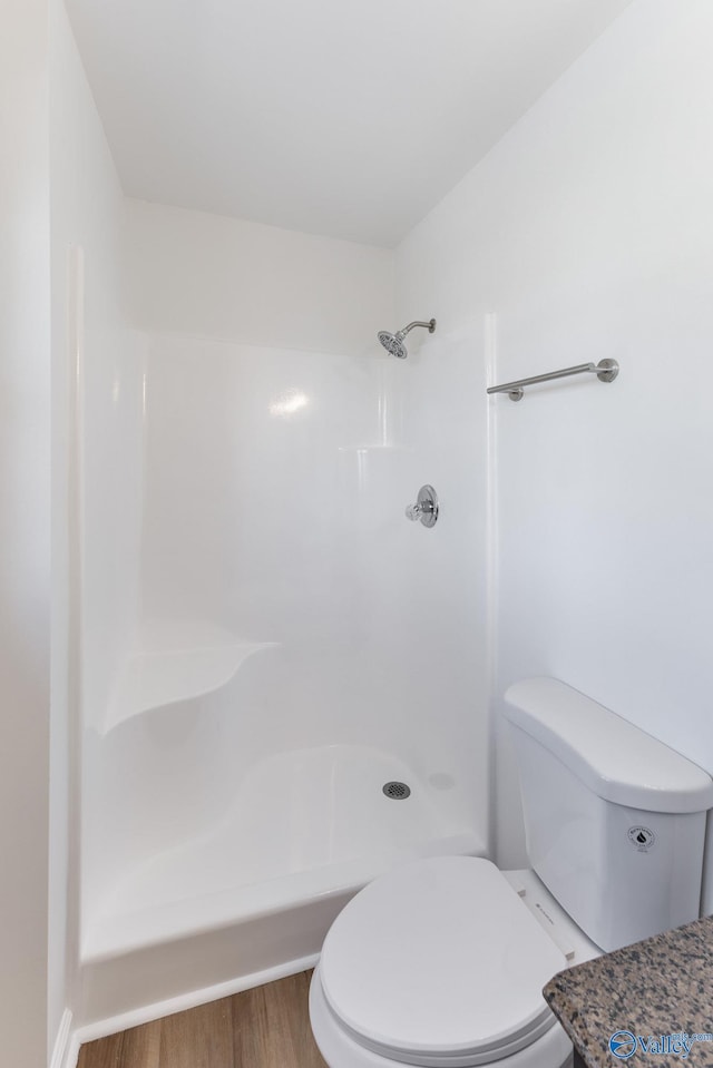 full bathroom with a shower, wood finished floors, and toilet