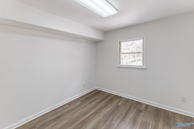 spare room featuring baseboards and wood finished floors