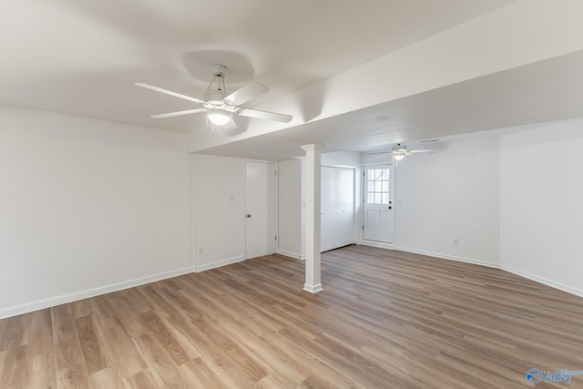 below grade area featuring light wood finished floors, baseboards, and a ceiling fan