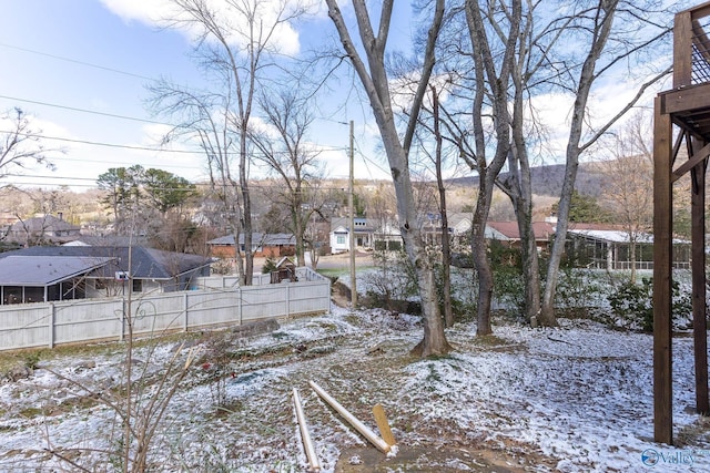 yard covered in snow featuring a residential view and fence