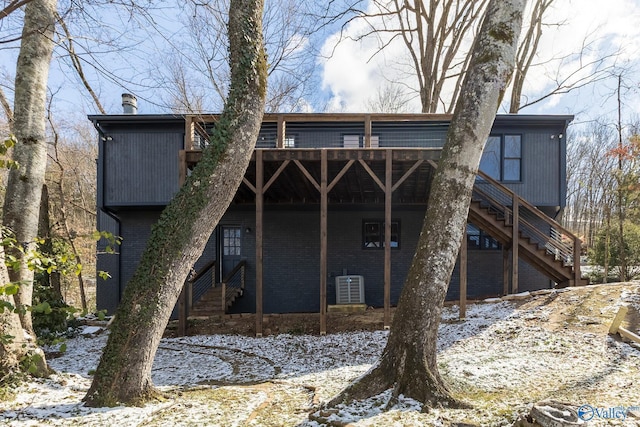 snow covered property featuring brick siding and central air condition unit