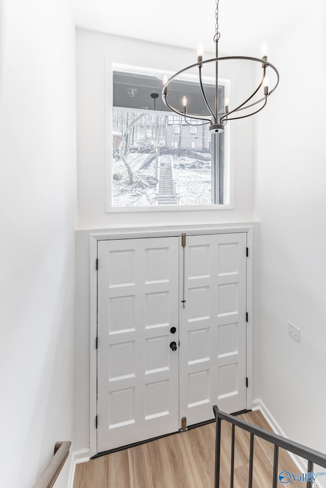 foyer entrance featuring baseboards, a notable chandelier, and light wood finished floors