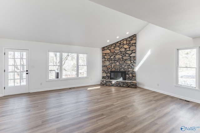 unfurnished living room with a fireplace, wood finished floors, visible vents, and a healthy amount of sunlight