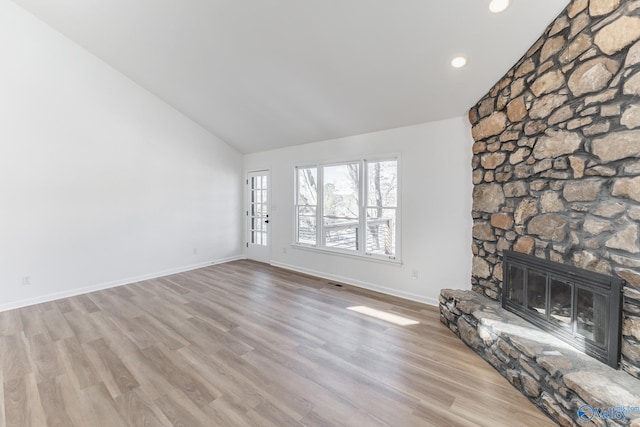 unfurnished living room featuring light wood-type flooring, lofted ceiling, a stone fireplace, and baseboards