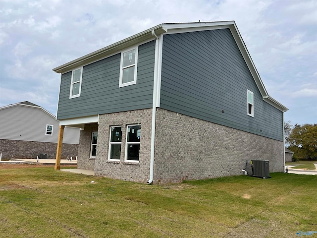 back of property featuring central AC unit and a lawn