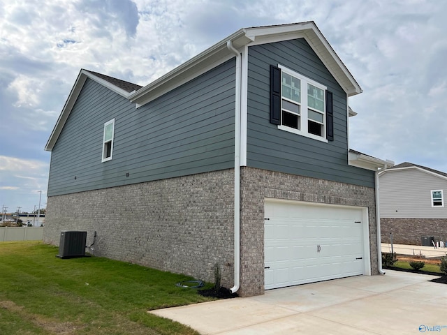 view of side of property with a yard, a garage, and central air condition unit