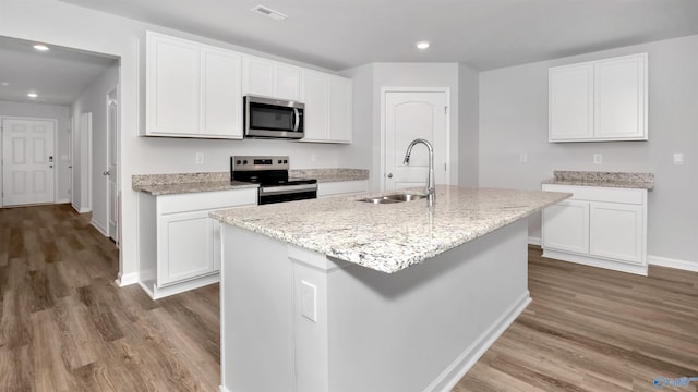 kitchen featuring sink, a center island with sink, hardwood / wood-style flooring, stainless steel appliances, and white cabinets