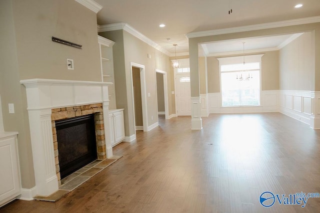 207 Somerton Dr, Huntsville, AL 35811 - unfurnished living room with a stone fireplace, wood finished floors, a decorative wall, wainscoting, and crown molding