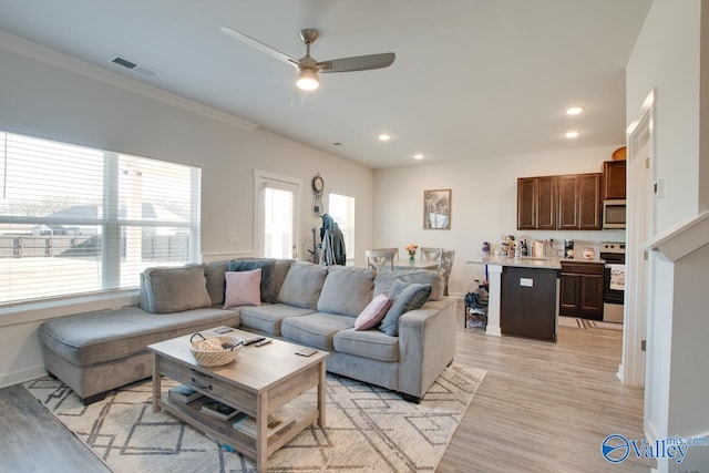 living room with ceiling fan, plenty of natural light, and light hardwood / wood-style flooring