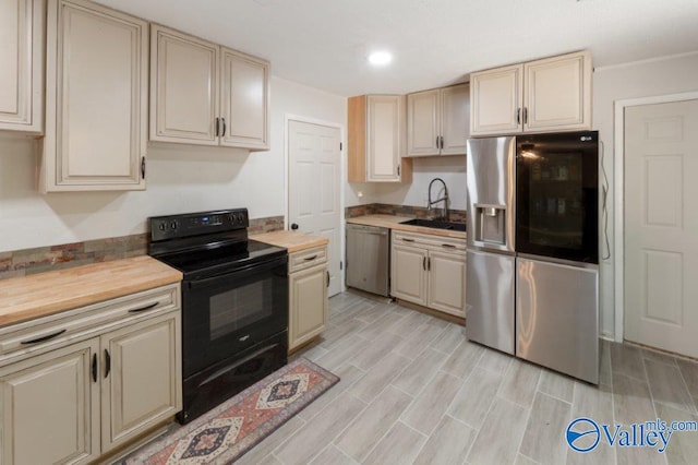 kitchen with cream cabinets, appliances with stainless steel finishes, and a sink