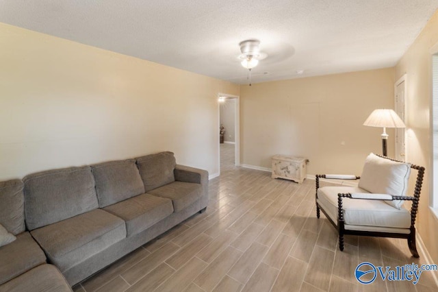 living area featuring light wood-style floors, baseboards, and ceiling fan