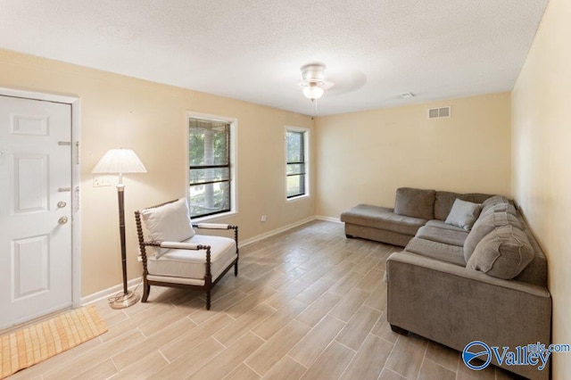 living area with baseboards, a ceiling fan, visible vents, and light wood-type flooring