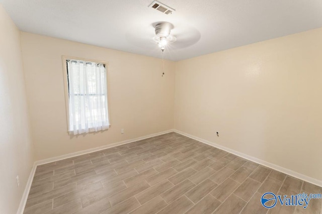 empty room with wood finished floors, visible vents, a ceiling fan, and baseboards