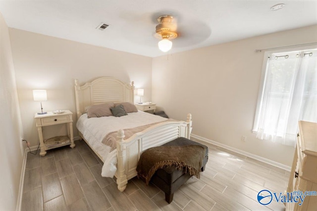 bedroom with wood tiled floor, visible vents, a ceiling fan, and baseboards