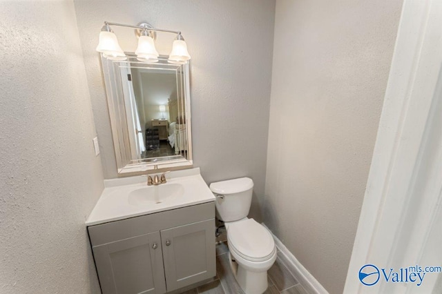 bathroom featuring toilet, vanity, and baseboards
