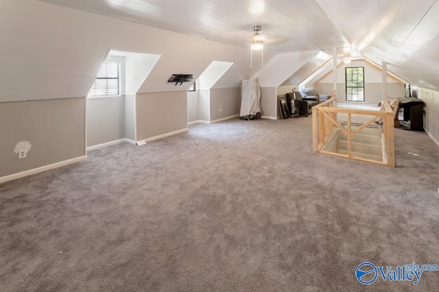 bonus room featuring lofted ceiling, carpet flooring, baseboards, and ceiling fan