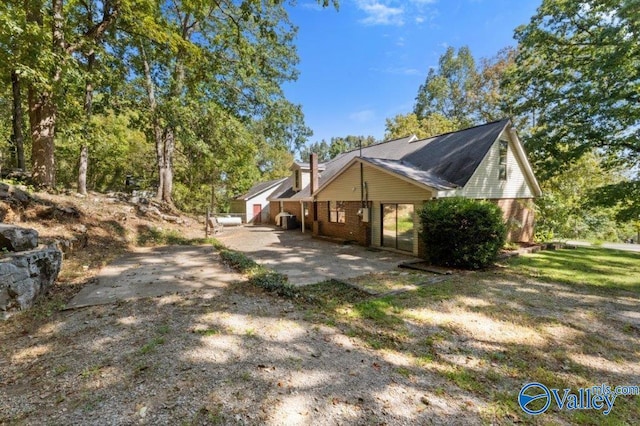 view of property exterior with brick siding and a patio area