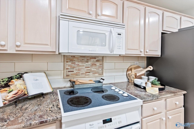 kitchen featuring white microwave, light stone counters, electric cooktop, and backsplash