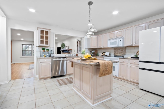 kitchen with tasteful backsplash, white appliances, light tile patterned flooring, and a center island