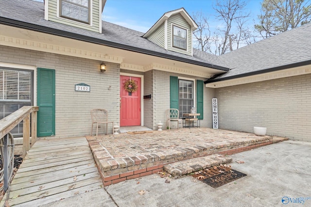 entrance to property with brick siding and roof with shingles