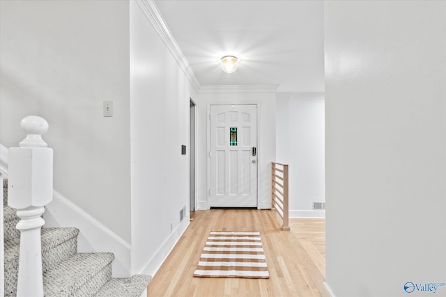 entrance foyer with visible vents, crown molding, light wood-style flooring, and baseboards