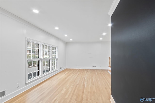 unfurnished room featuring light wood finished floors, baseboards, and crown molding