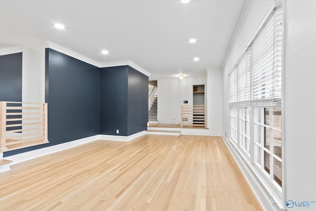 spare room featuring baseboards, stairway, crown molding, and wood finished floors