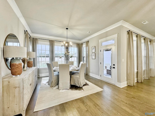 dining area with hardwood / wood-style flooring, crown molding, and a chandelier