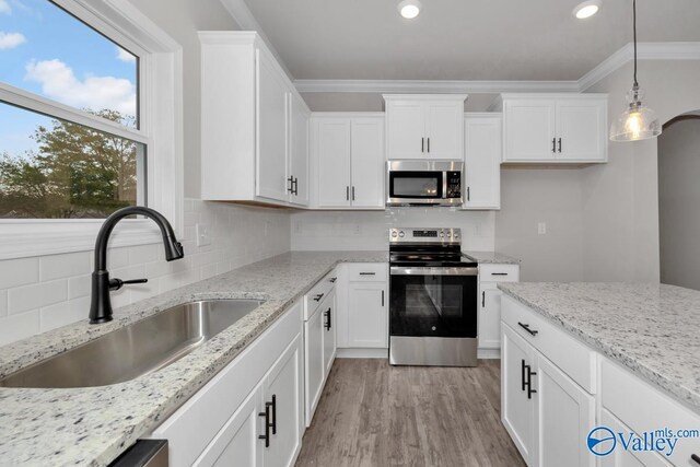 kitchen featuring sink, decorative backsplash, ornamental molding, appliances with stainless steel finishes, and decorative light fixtures