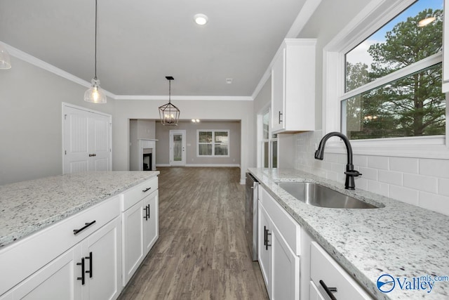 kitchen with white cabinets, hardwood / wood-style floors, light stone counters, and sink