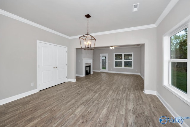 unfurnished living room with ornamental molding, a healthy amount of sunlight, ceiling fan with notable chandelier, and wood-type flooring