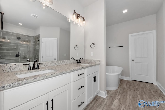 bathroom featuring hardwood / wood-style floors, vanity, and plus walk in shower