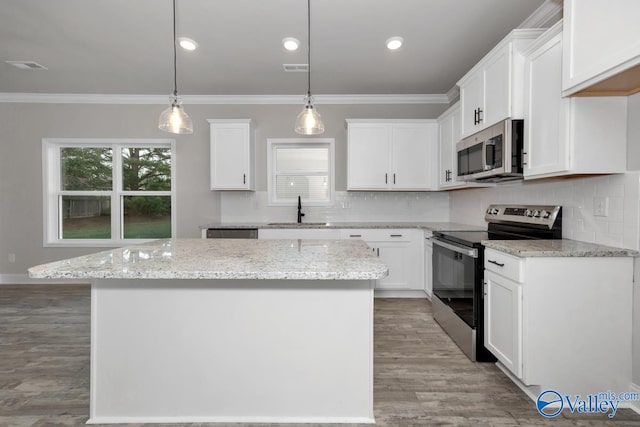 kitchen featuring white cabinetry, sink, hanging light fixtures, stainless steel appliances, and a kitchen island