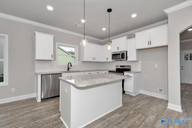 kitchen featuring stainless steel appliances, crown molding, a center island, light hardwood / wood-style floors, and white cabinetry