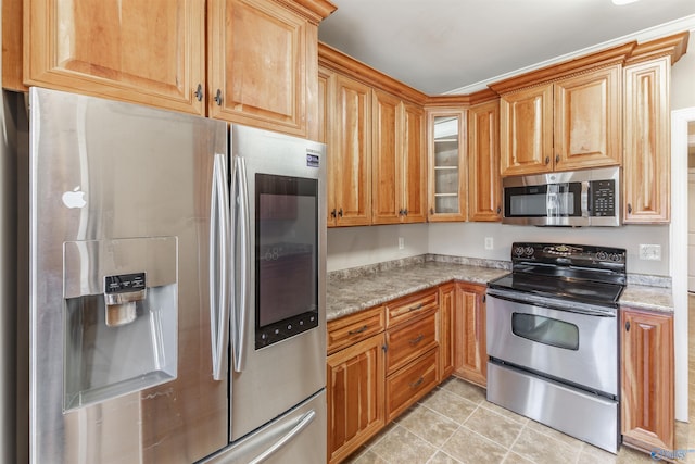 kitchen with light stone countertops, light tile patterned floors, and stainless steel appliances