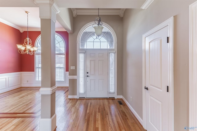 foyer entrance with decorative columns, crown molding, light hardwood / wood-style flooring, and a chandelier