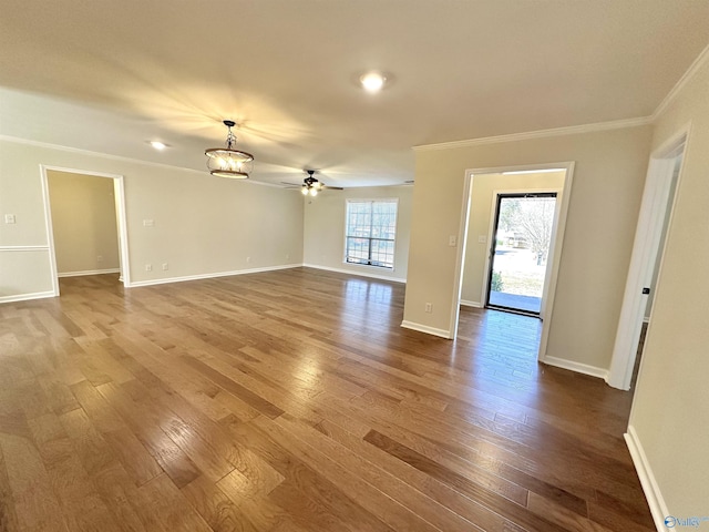 spare room with crown molding, wood-type flooring, and ceiling fan with notable chandelier