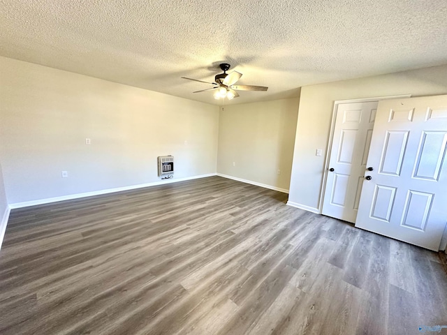 empty room featuring heating unit, a textured ceiling, dark hardwood / wood-style flooring, and ceiling fan