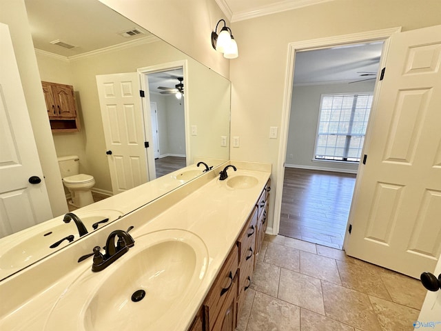 bathroom with tile patterned floors, toilet, ornamental molding, vanity, and ceiling fan