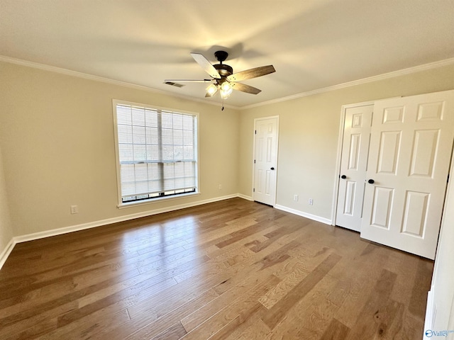 unfurnished bedroom with hardwood / wood-style flooring, ornamental molding, multiple closets, and ceiling fan