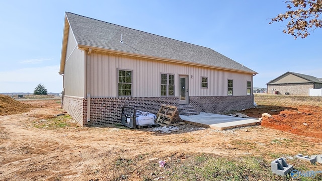 back of property featuring brick siding and roof with shingles