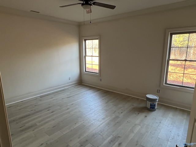 spare room featuring visible vents, ornamental molding, a ceiling fan, wood finished floors, and baseboards