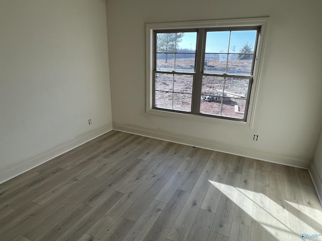 spare room with baseboards and wood finished floors