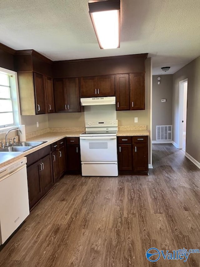kitchen with a sink, white appliances, a textured ceiling, under cabinet range hood, and visible vents