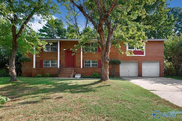 split foyer home featuring an attached garage, a front yard, concrete driveway, and brick siding